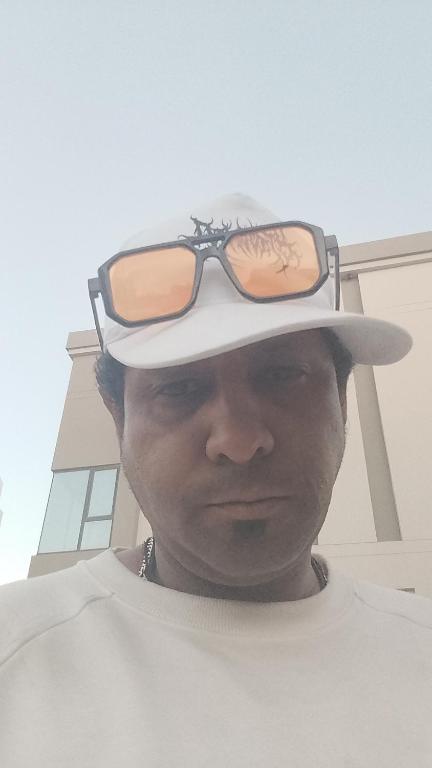 a man wearing a hat with sunglasses on top at Hamad in Madīnat Ḩamad
