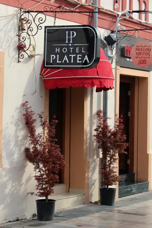 ein Hotel mit zwei Topfbäumen vor einem Gebäude in der Unterkunft Hotel Platea in Shkodra