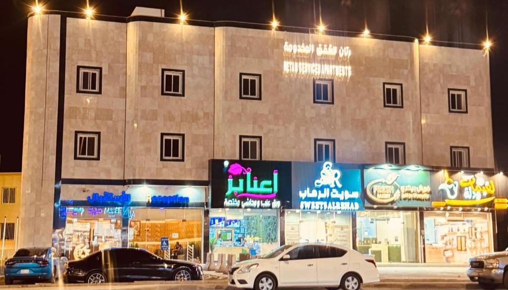 two cars parked in front of a building at night at رتان للشقق المخدومة in Khamis Mushayt