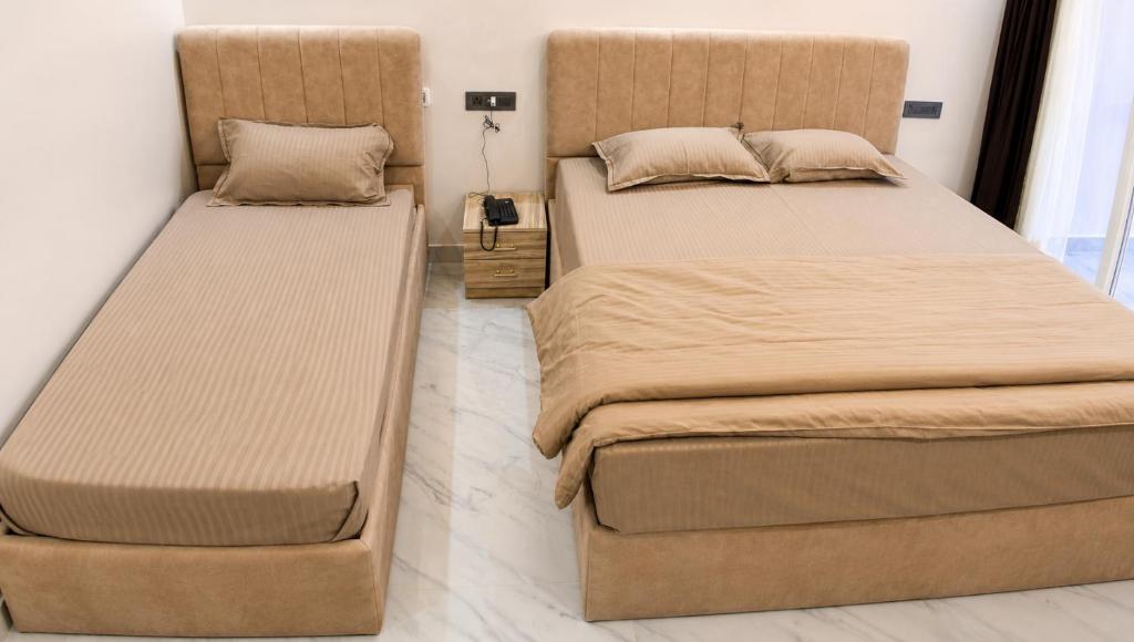 two beds sitting next to each other in a room at Hotel Silver Oak in Dehradun