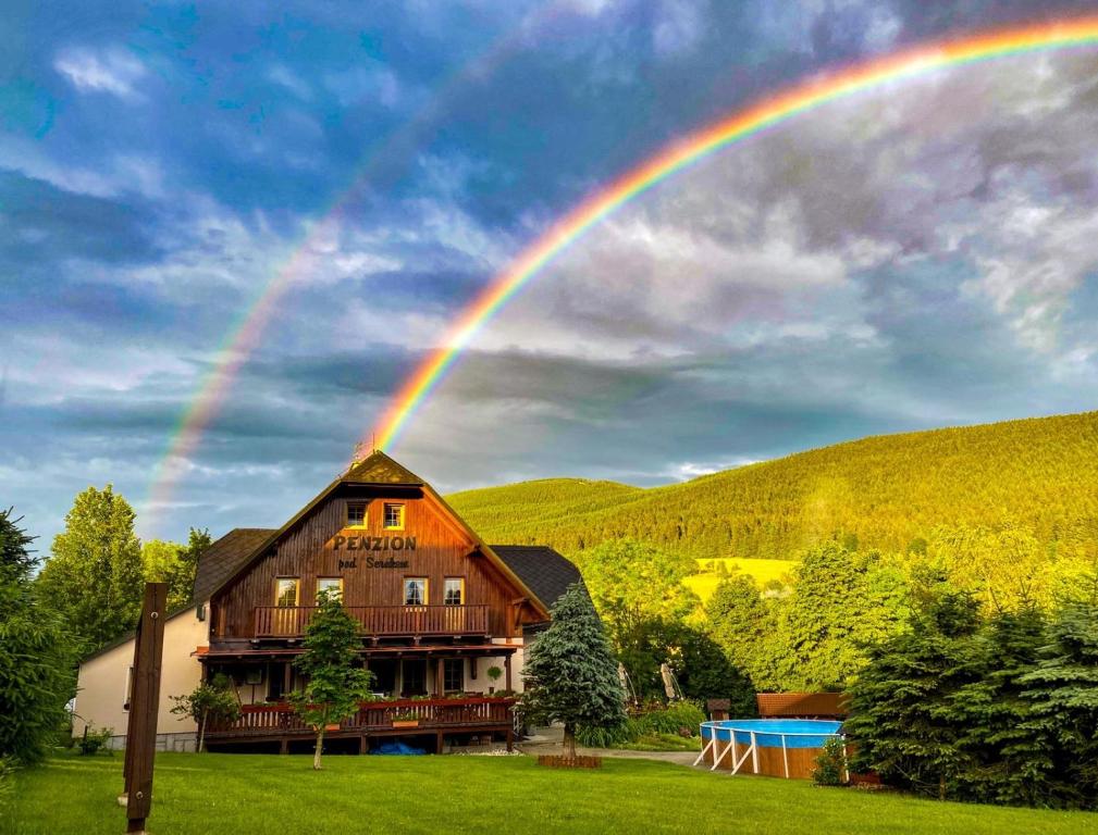 a rainbow over a home with a house at Penzion pod Šerákem in Ostružná