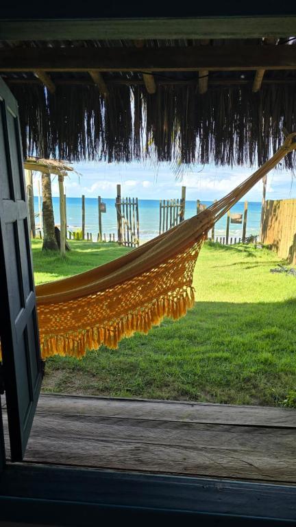 a hammock in a house with a view of the ocean at Vila Ohana Beira Mar - Caraíva in Caraíva