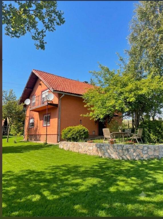 a house with a stone wall and a yard at HERC domaćinstvo in Nova Varoš