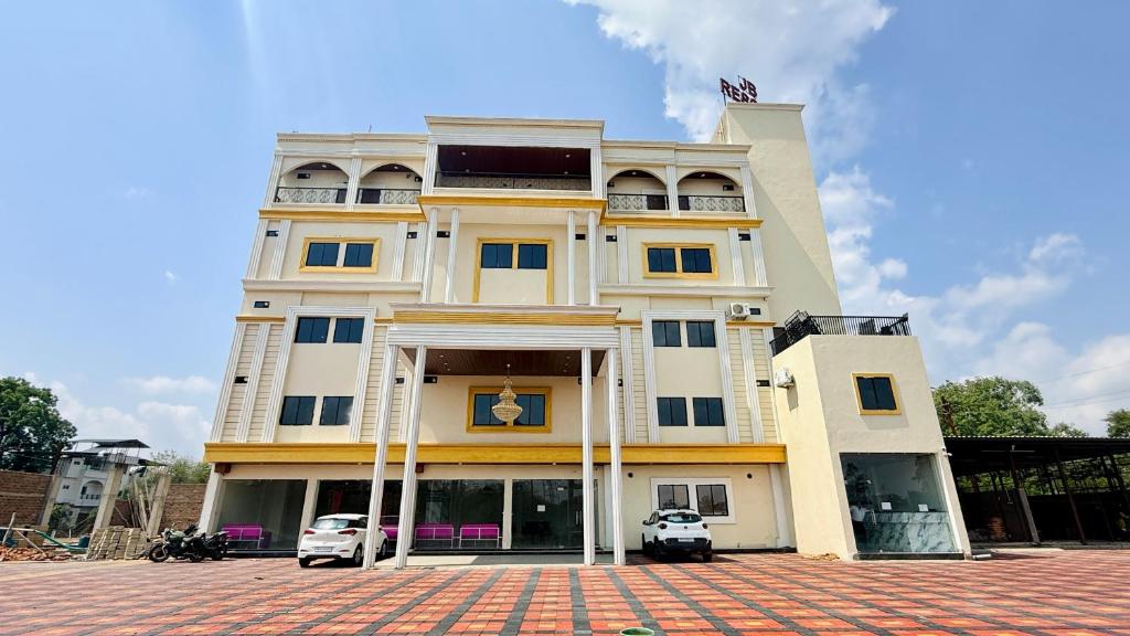 a large building with two cars parked in front of it at JB Resort in Mhow