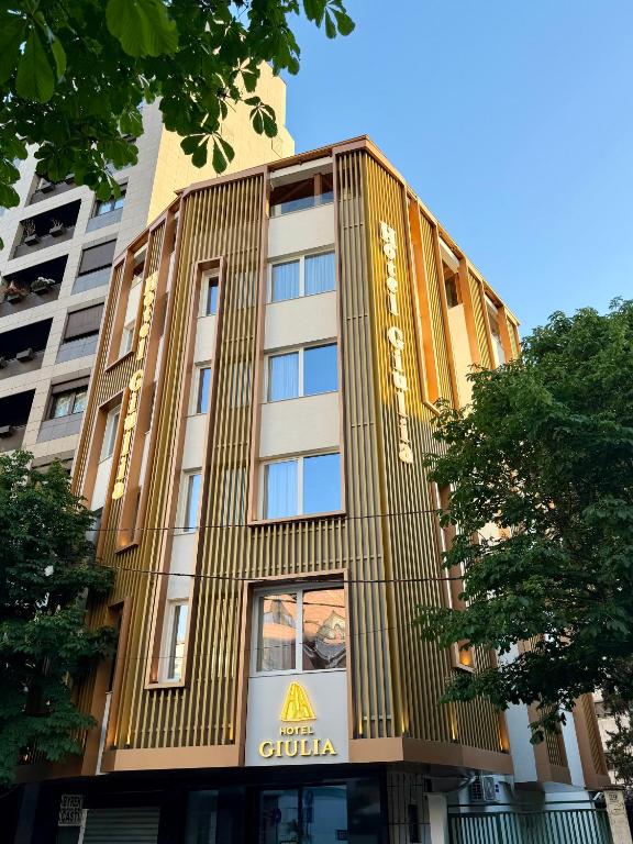 a tall yellow building with aania sign on it at Giulia Center Hotel in Tirana