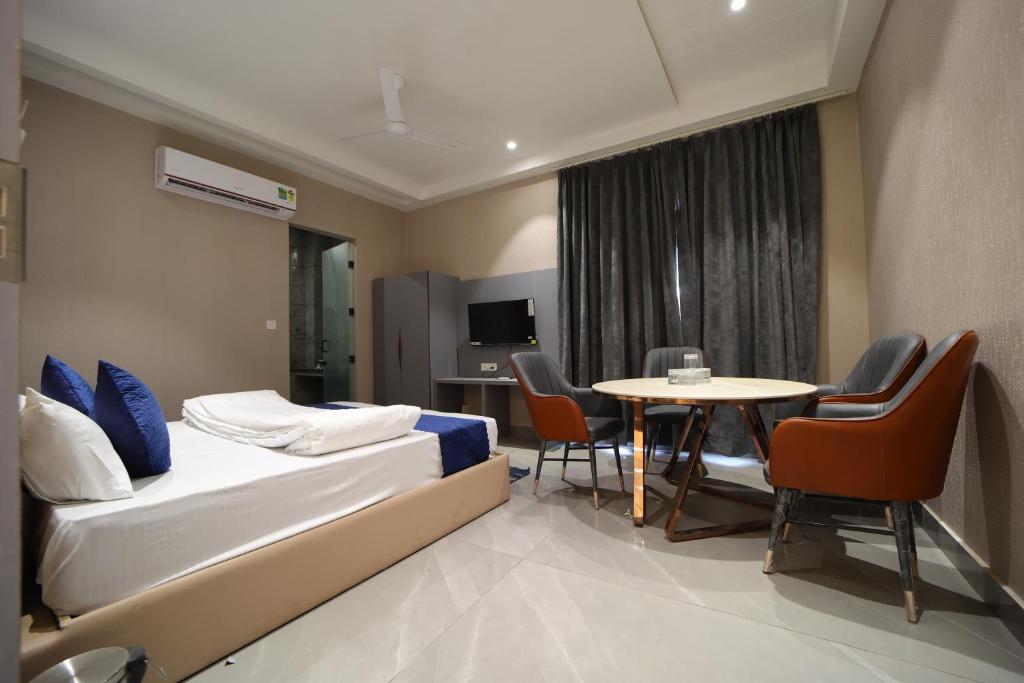 a hotel room with a bed and a table and chairs at Hotel Vantara in Karnāl