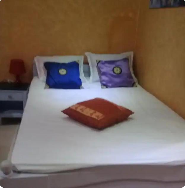 a white bed with blue and purple pillows on it at l'Olivier in La Goulette