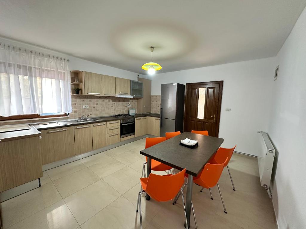 eine Küche mit einem schwarzen Tisch und orangefarbenen Stühlen in der Unterkunft Catana in Arad