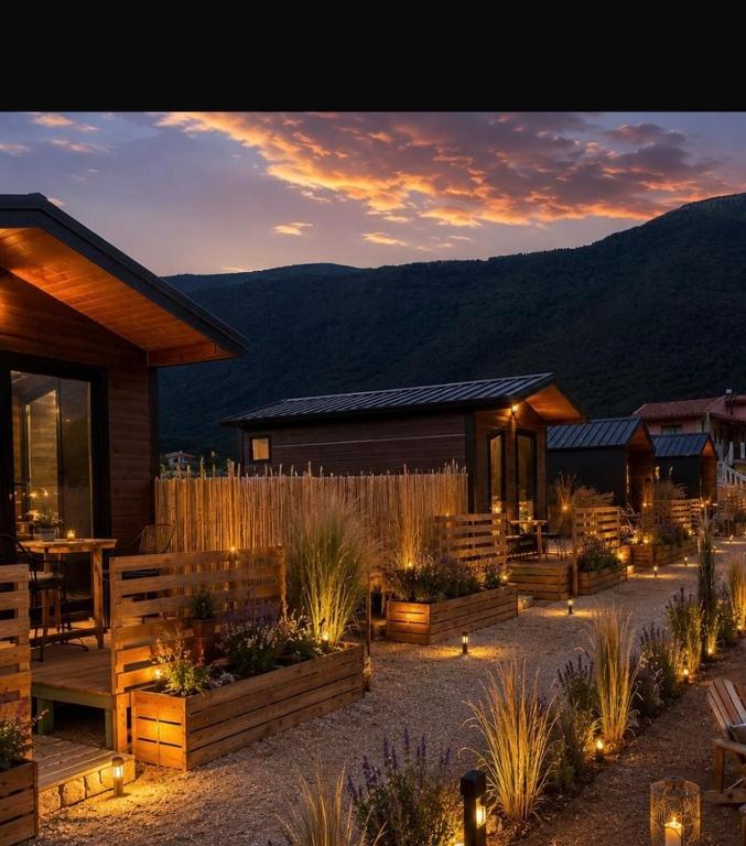 ein Garten mit einem Haus, das von einem Zaun umgeben und mit Lichtern beleuchtet ist in der Unterkunft Lean chalet Sea&Mountain view in Dukat