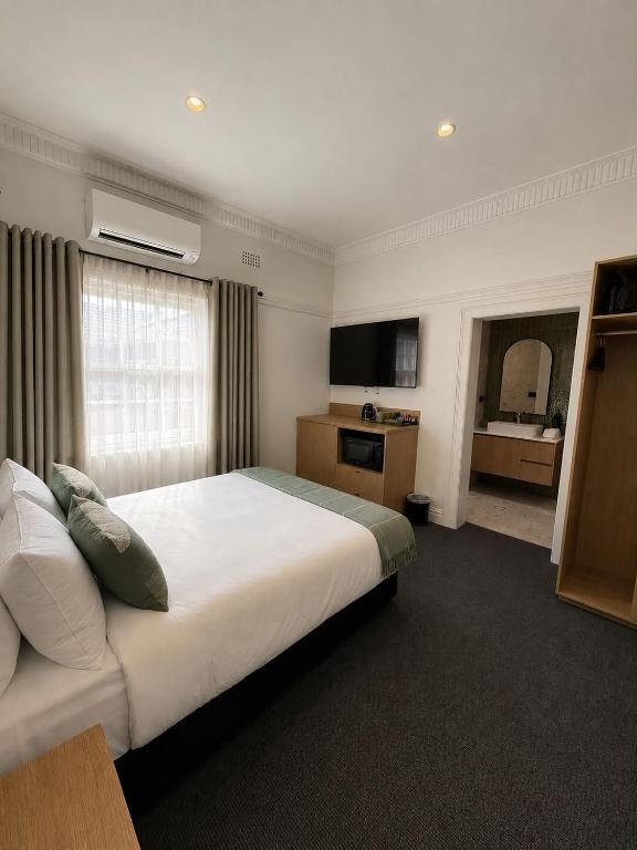 a hotel room with a large bed and a bathroom at Tourist Hotel Queanbeyan in Queanbeyan