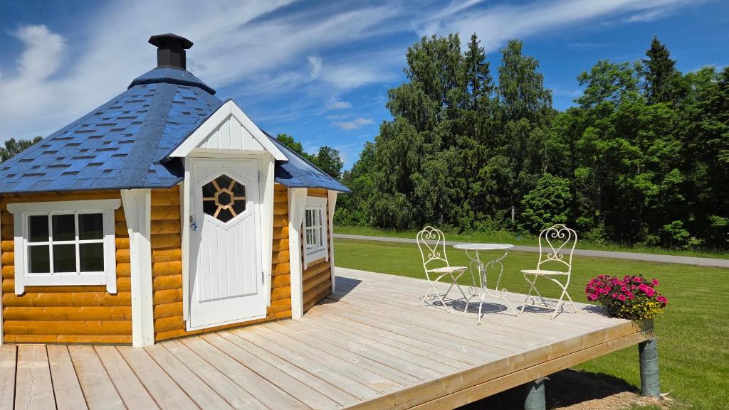 a wooden deck with a small house with a table and chairs at Antsu Puhkeala Matkamaja in Nüpli
