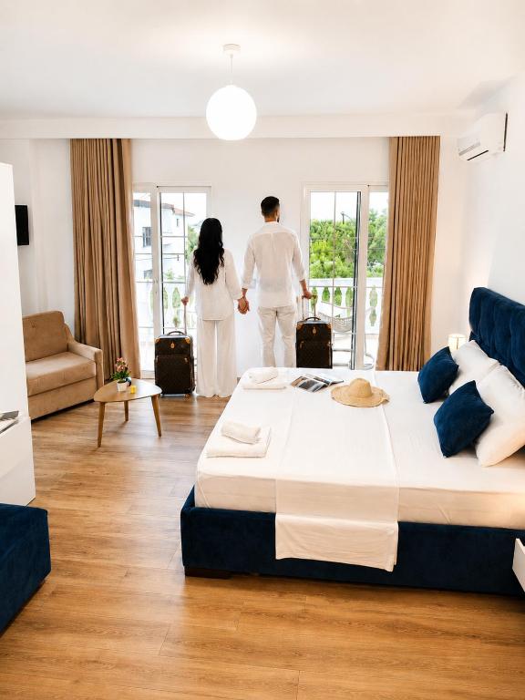 a man and woman in a bedroom with a large bed at Vasiliu Boutique Hotel Ksamil in Ksamil