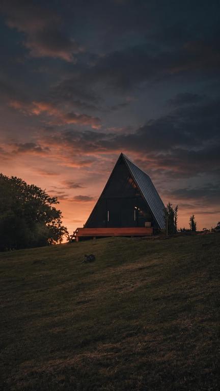 a barn sitting on top of a field at sunset at Cabanas Terra Nova in Três Coroas