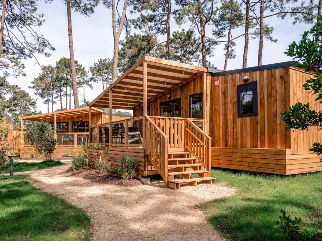 a wooden cabin with a staircase in the grass at Camping LANDAE in Ondres