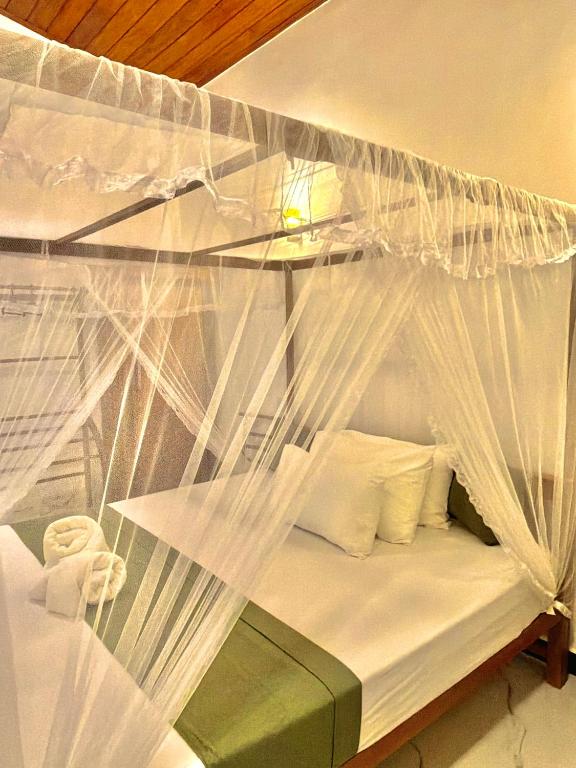 a bed with a canopy with white mosquito nets at villa Senoa in Ahangama