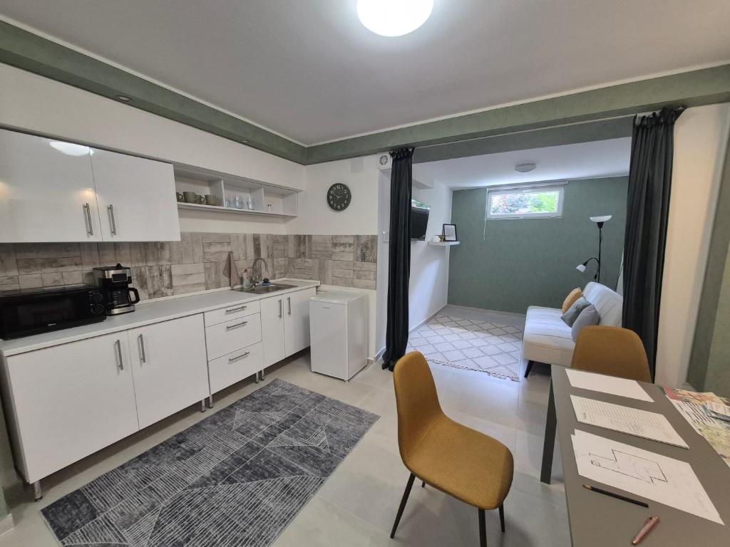 a kitchen with white cabinets and a living room at Da Vinci Apartmanok in Eger