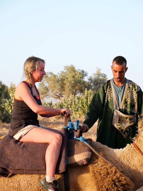 a man and a woman sitting on a sheep at Camp la mer de sable in Mhamid