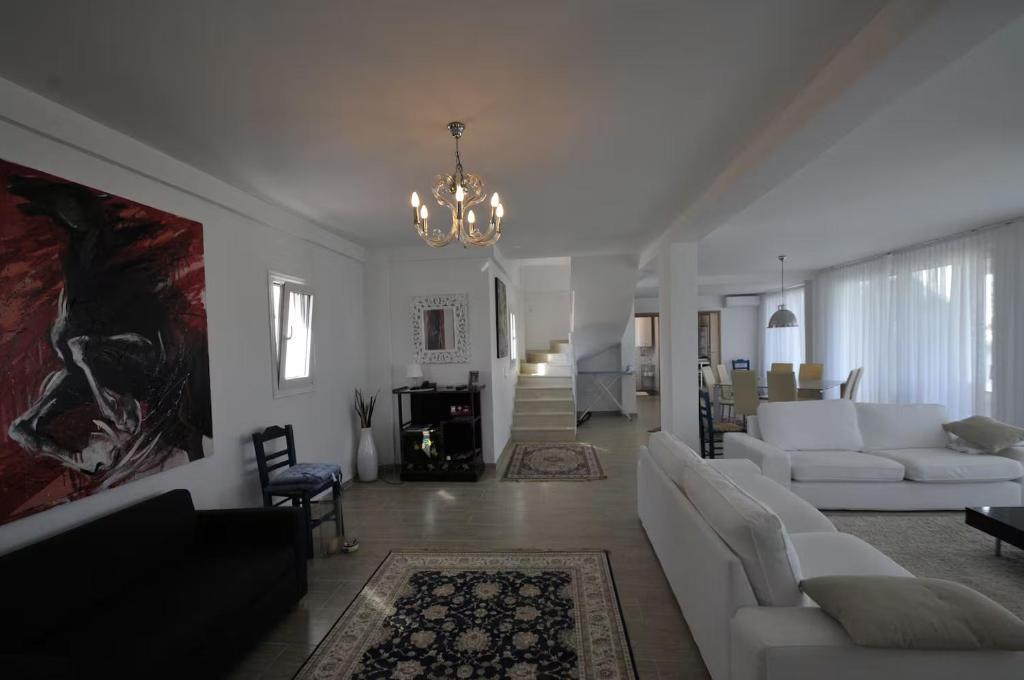 a living room with white furniture and a chandelier at Villa Lina Kerkira in Gouvia