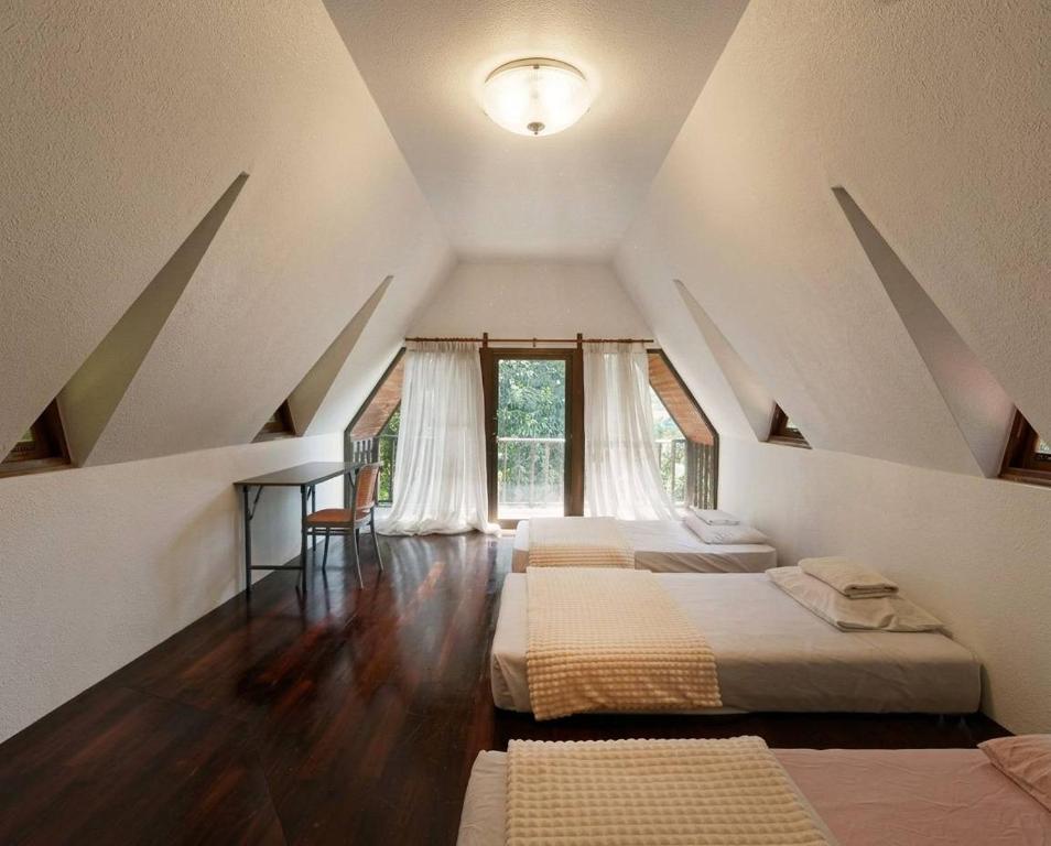 a attic room with three beds and a window at SN Garden in Ban Bo Hin