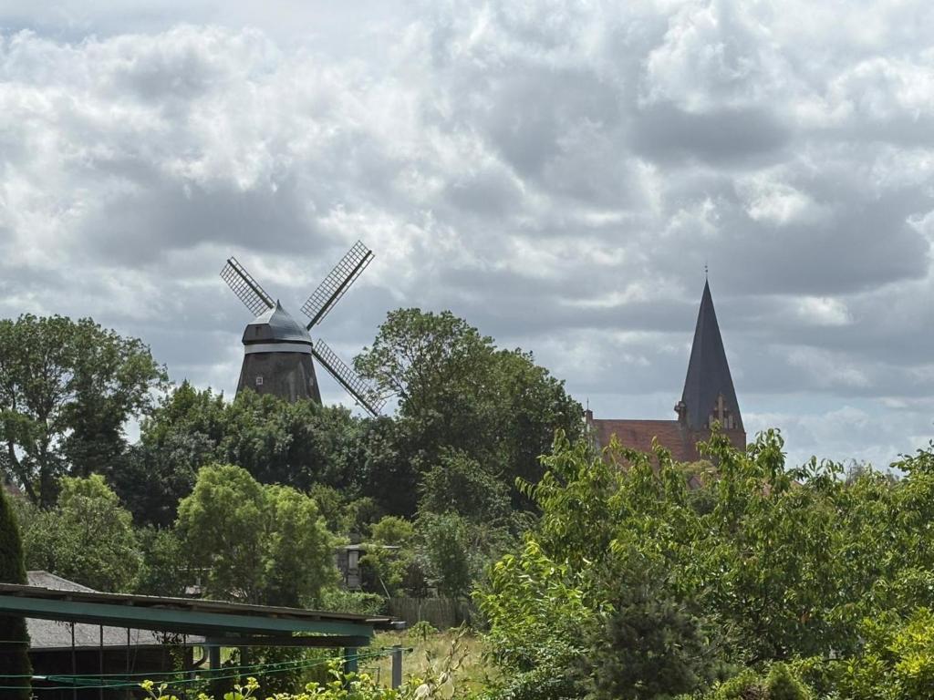 a windmill and a church and a building and trees at Ferienwohnung im Ort in Röbel