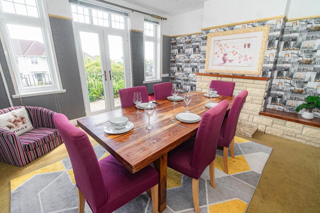 a dining room with a wooden table and purple chairs at Gateway to Gower in Dunvant