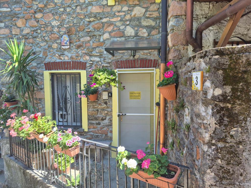 a stone building with a door and flowers on it at Ca' di Ruchitt in Cuasso Al Monte