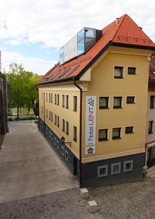 a yellow building with a red roof with a window at Hotel Lent in Maribor