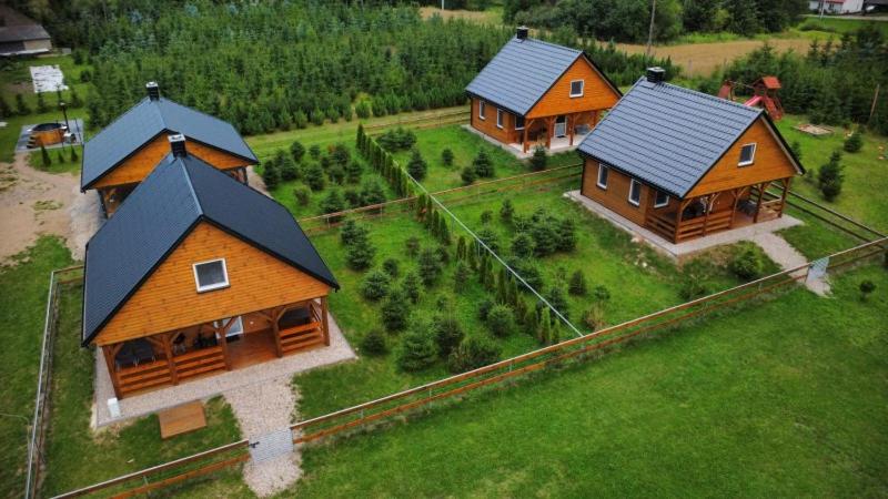 two log homes on a green field with at Przystanek Ładnówko in Kruszyny Szlacheckie