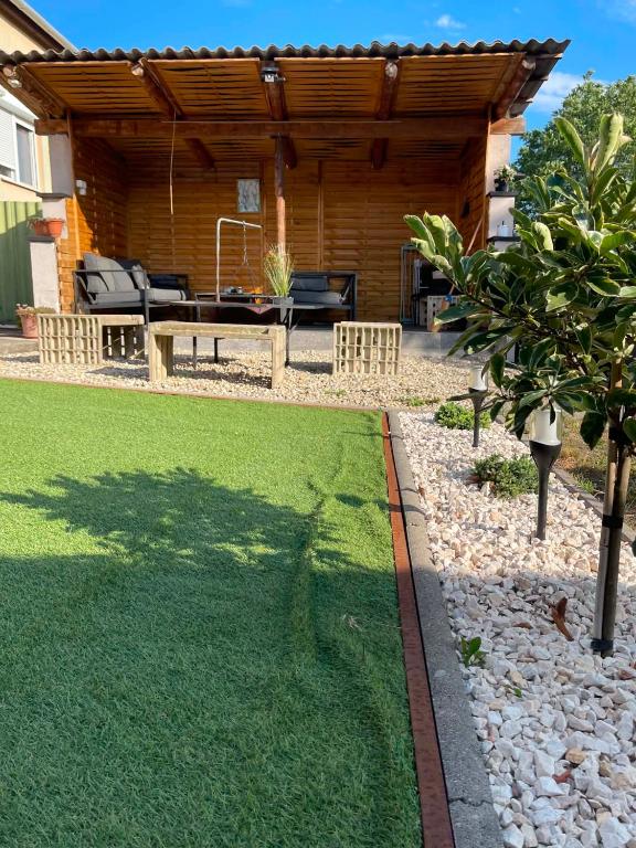 a backyard with a wooden cabin with a bench and grass at Kaland vendégház in Sátoraljaújhely