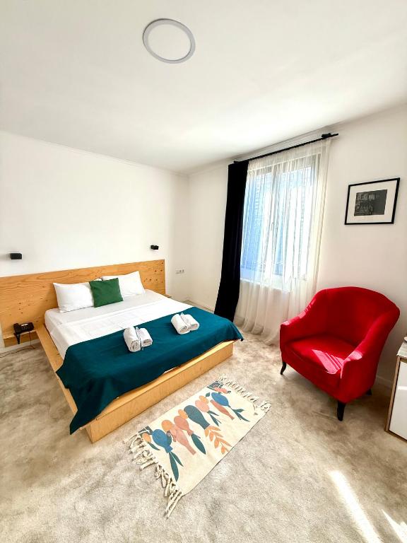 a bedroom with a bed and a red chair at Opera City Center Hotel in Tbilisi City