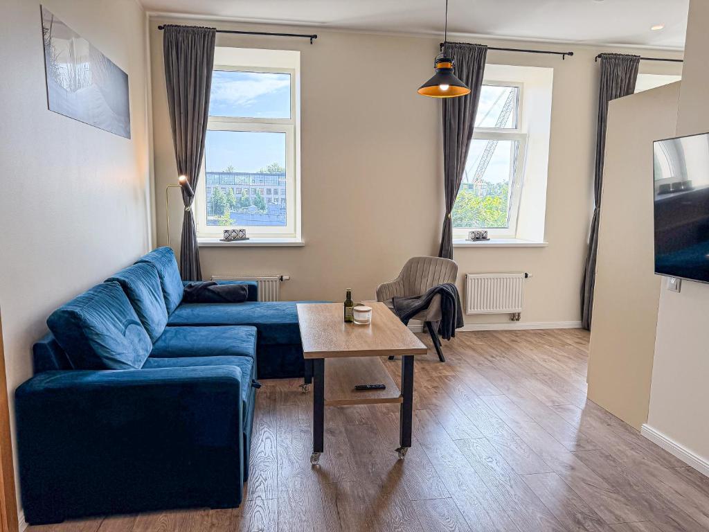 a living room with a blue couch and a table at Cozy Apartment Kaija in Liepāja