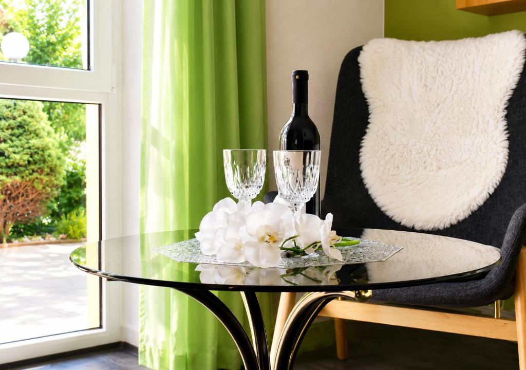 a glass table with a bottle of wine and two glasses at Siebers-Ferienwohnung in Saupsdorf