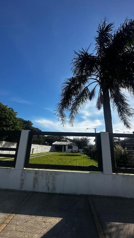 a fence with a palm tree and a palm tree at Canto dos pássaros in Tramandaí