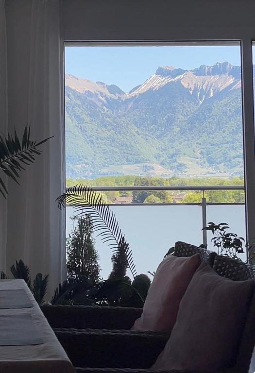 a living room with a couch and a large window at Lake Geneva in Port-Valais