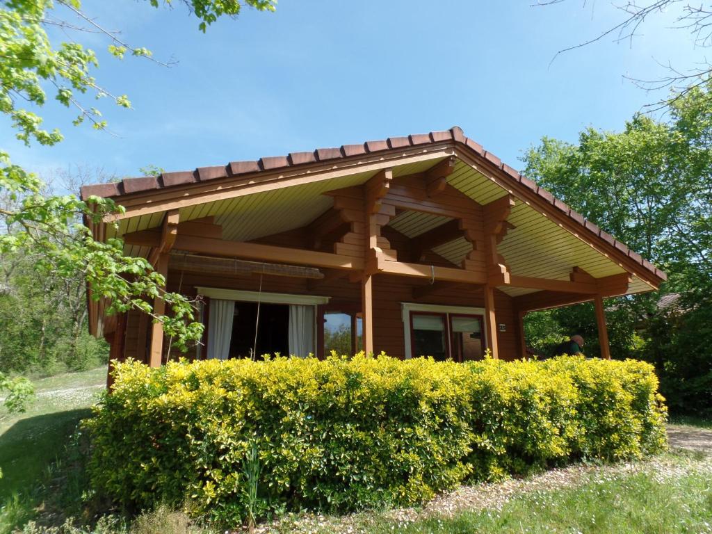 a wooden house with a bush in front of it at Chalet le Chal'Heureux in Mauroux