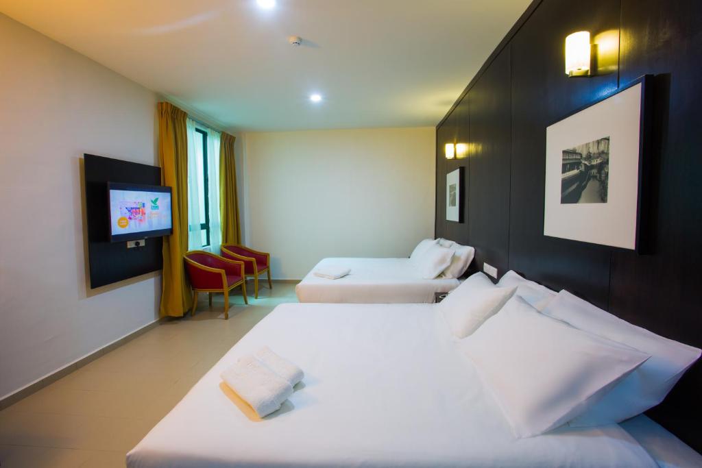 um quarto de hotel com duas camas e uma televisão de ecrã plano em Akar Hotel Jalan TAR em Kuala Lumpur