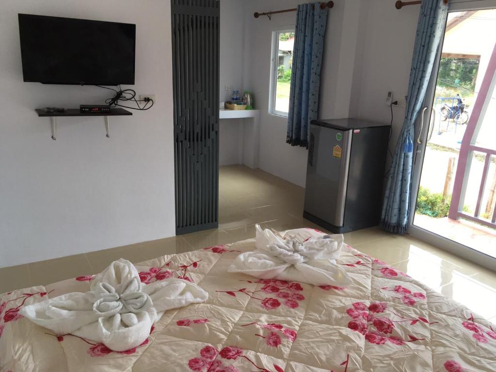 a bed with towels on top of it with a television at Baan Sri Lanta Sand in Ko Lanta