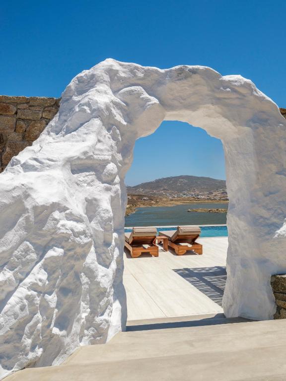 a stone archway with picnic tables on a patio at Vinara Luxury Suites Mykonos in Mykonos