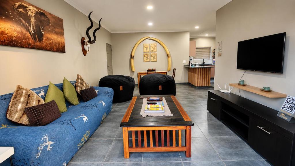 a living room with a blue couch and a tv at Lloyds - unit 10 in Ermelo