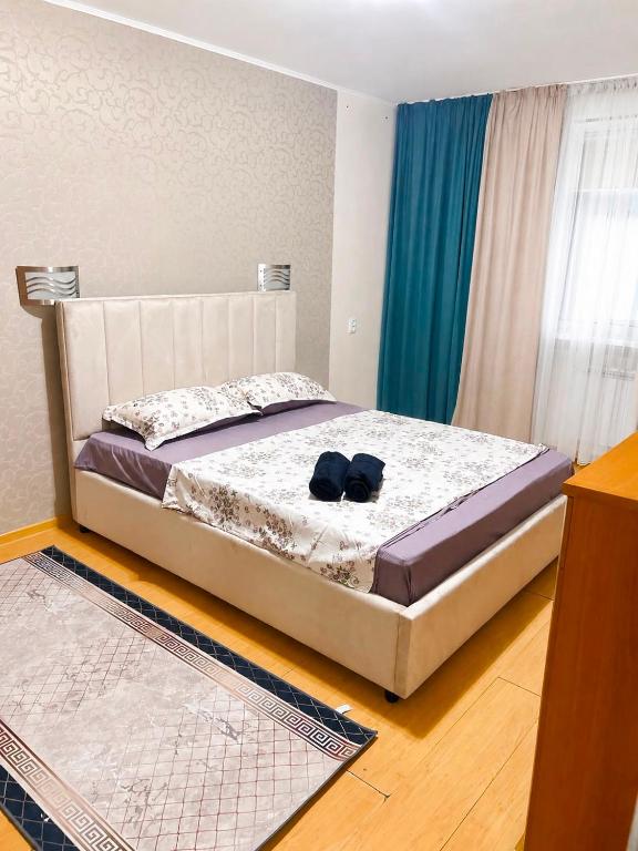 a bedroom with a bed with a pair of shoes on it at Квартира Иртыш in Pavlodar