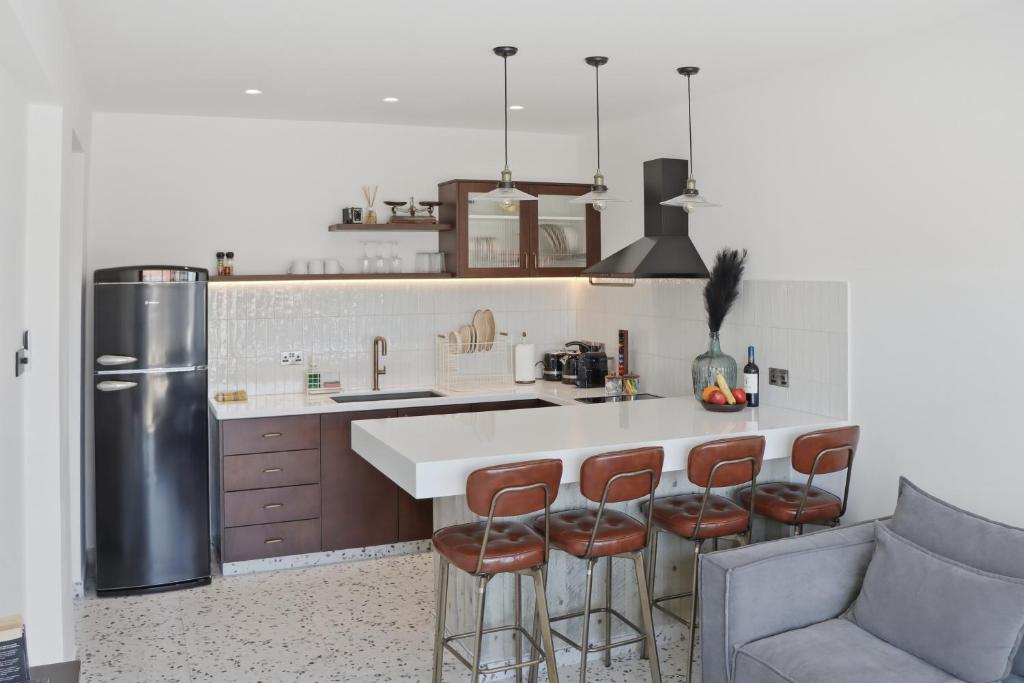 a kitchen with a large white counter and bar stools at The Retro Suite Kato Paphos 2 min to the beach in Paphos