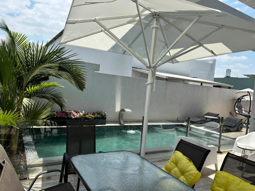 a patio with a table and an umbrella and a swimming pool at Geron's וילת אירוח in Bet Sheʼan