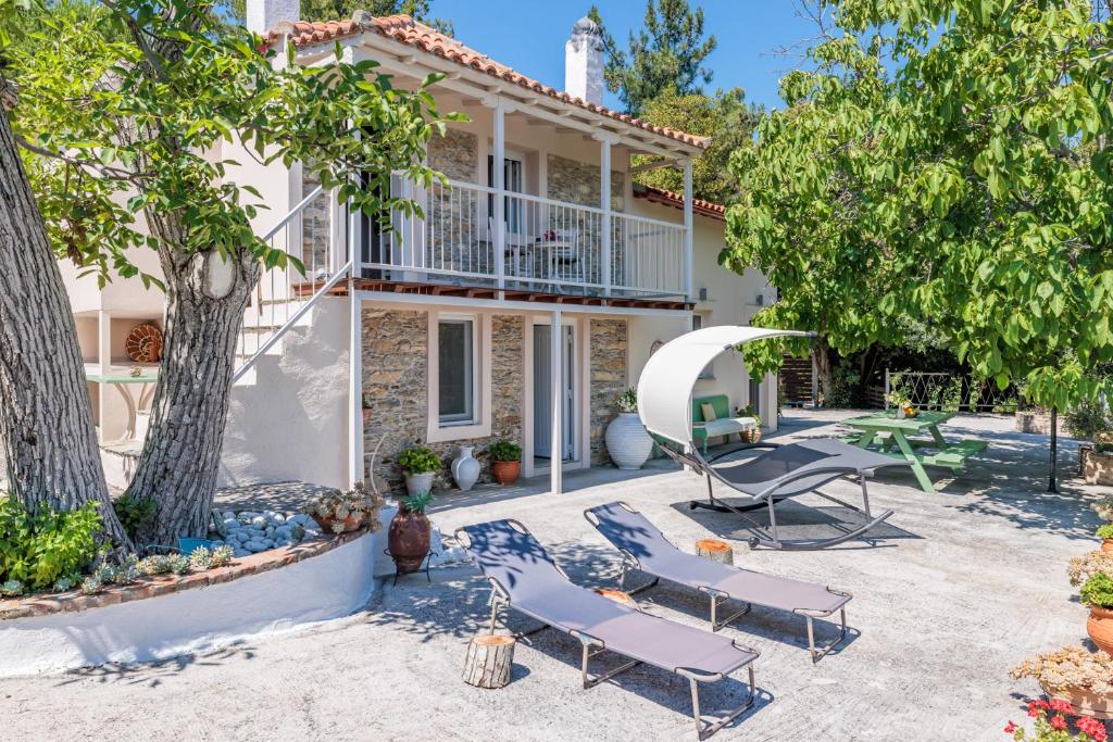 an exterior view of a house with chairs and trees at Pyrgos Country House in Skopelos Town