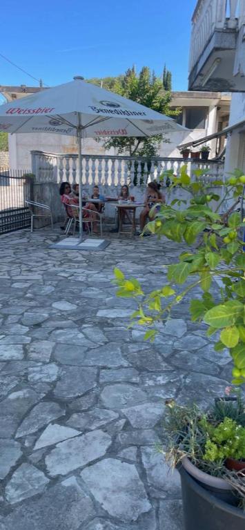 eine Terrasse mit Menschen, die unter einem Sonnenschirm an Tischen sitzen. in der Unterkunft Bratica Domaća in Ulcinj