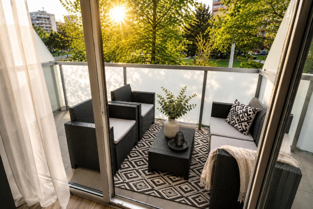 a balcony with a chair and a couch and a table at ALURE RESIDENCES 1 & 24h self check-in, free parking in front of the apartment building, new building, terrace, cafe with breakfast in the apartment building, next to the aqua park in Banská Bystrica