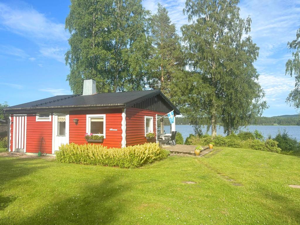 a small red and white house on a grass field at Schwedenhaus am See in Storfors