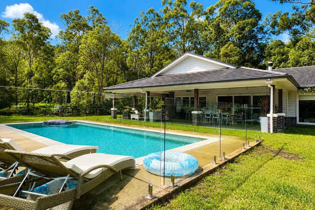 a swimming pool with chairs and a house at Spacious 6BR Mansion with Pool Sauna BBQ in Gold Coast