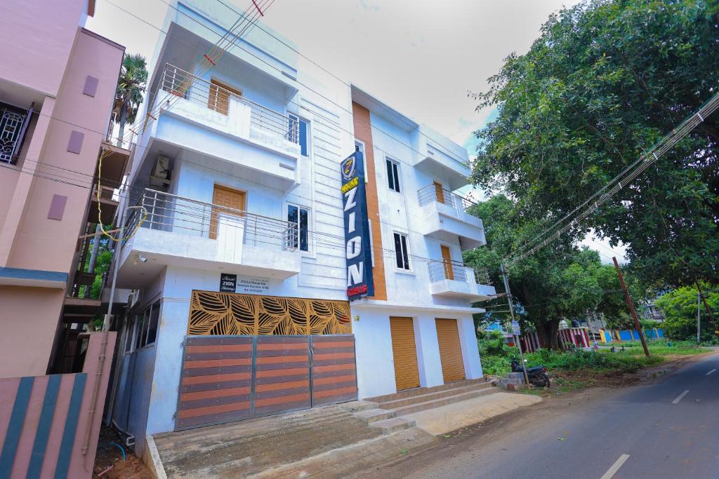a white building with a wooden door on a street at Mount Zion Holidays in Kuttālam