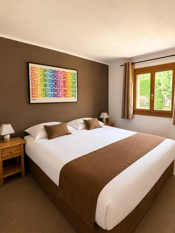 a bedroom with a large bed with a colorful painting on the wall at Hôtel Le Chastellan in Valberg