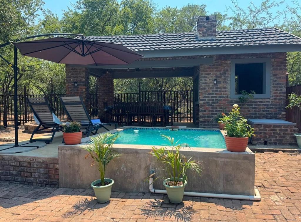 a patio with an umbrella and a swimming pool at La Bella Vita Marloth Park in Marloth Park